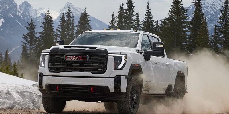 2026 GMC Sierra 2500 HD AT4X driving through rugged terrain demonstrating heavy-duty performance
